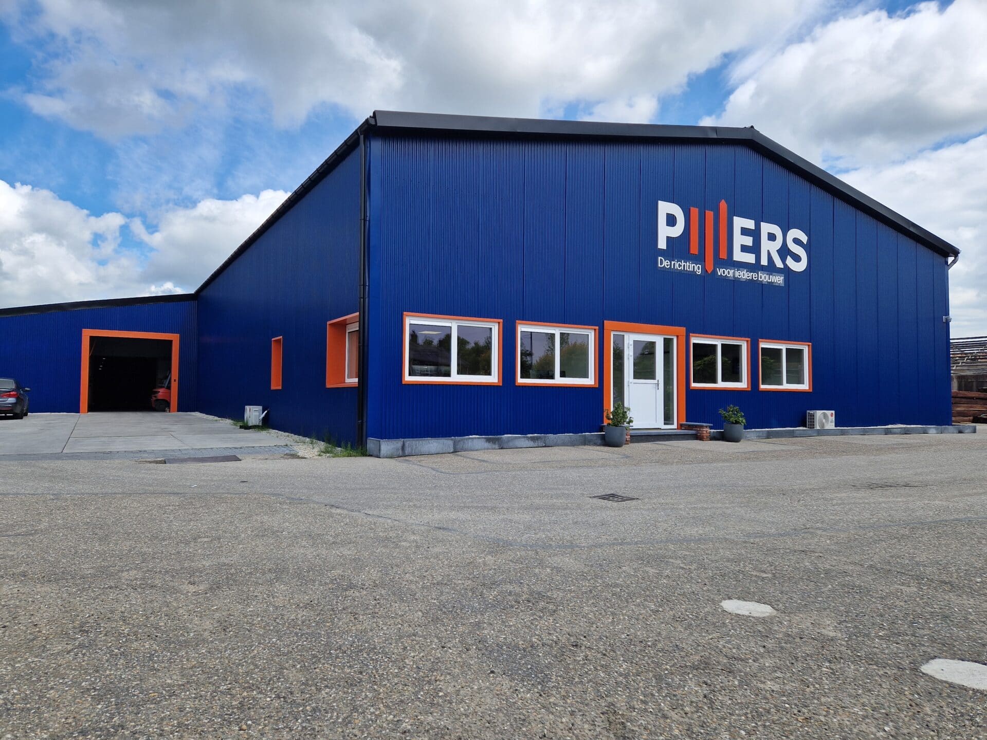 Kantoorgebouw met blauwe gevel en oranje accenten, Pijlers logo zichtbaar.