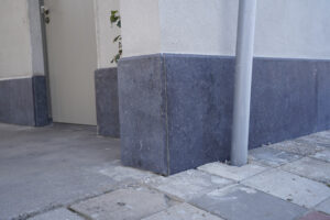 Pijlers en gevelafwerking met beton en steen, nabij deur en straat.